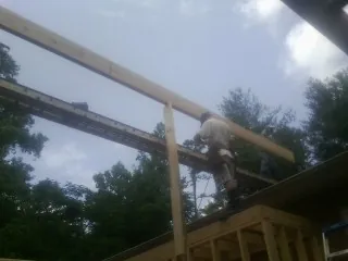 Carpenter setting a ridge beam over a new addition frame — Ice Dam Removal by Roofing Brothers in Medora