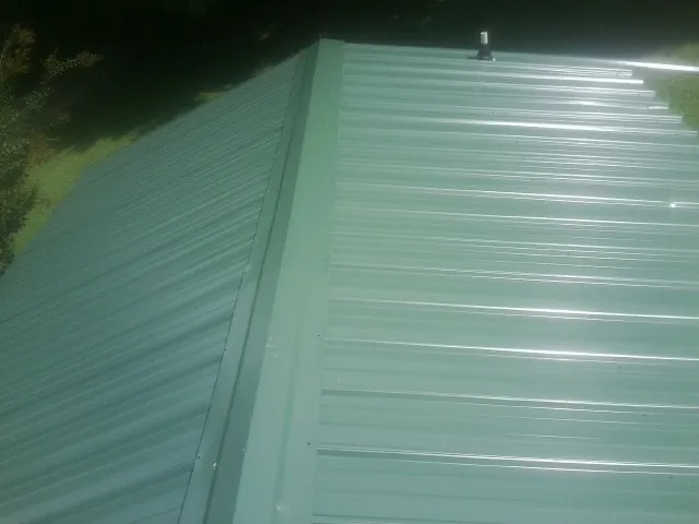 New green metal panels meeting at the ridge of a roof — Flat Roof Repair work by our crew in Medora
