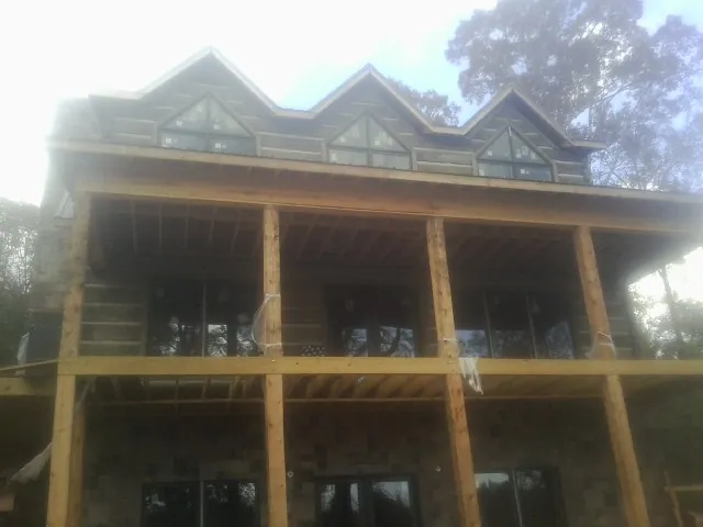 Dormers and porch framing on a large log home under construction — Roof Coating work by our crew in Medora