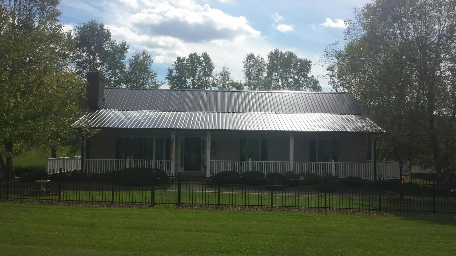Gray metal roof on a brick ranch with a full width front porch — Gutter Guard Installation work by our crew in Medora