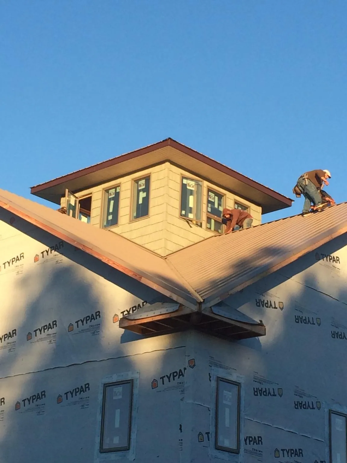 Roofers working around a rooftop cupola on a new metal roof at sunset — Roof Waterproofing in Medora by Roofing Brothers